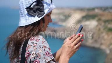 一个漂亮的女孩站在海边的斜坡上，在电话里写了一条信息。 高清，<strong>1920</strong>x1080。 慢动作。